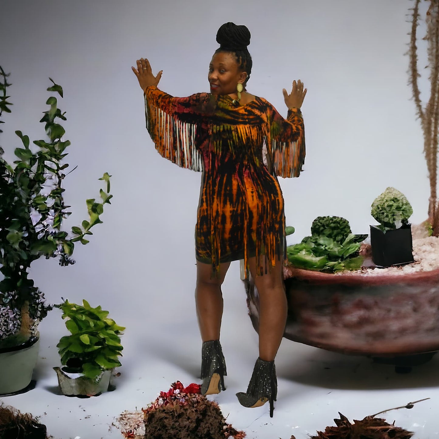Woman in a colorful dress standing among potted plants on a white background. SanJules