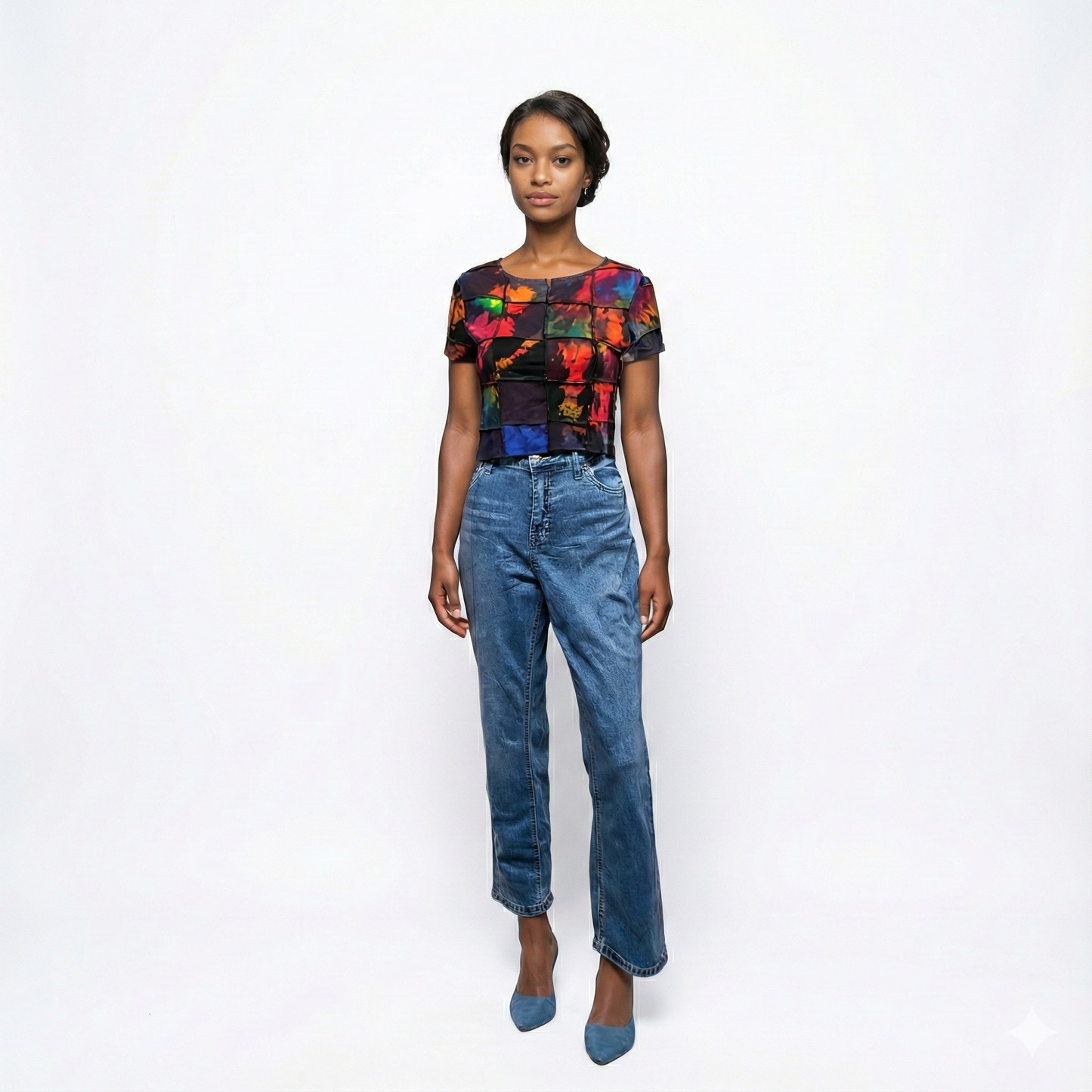 Woman wearing a colorful patchwork top and blue jeans on a white background