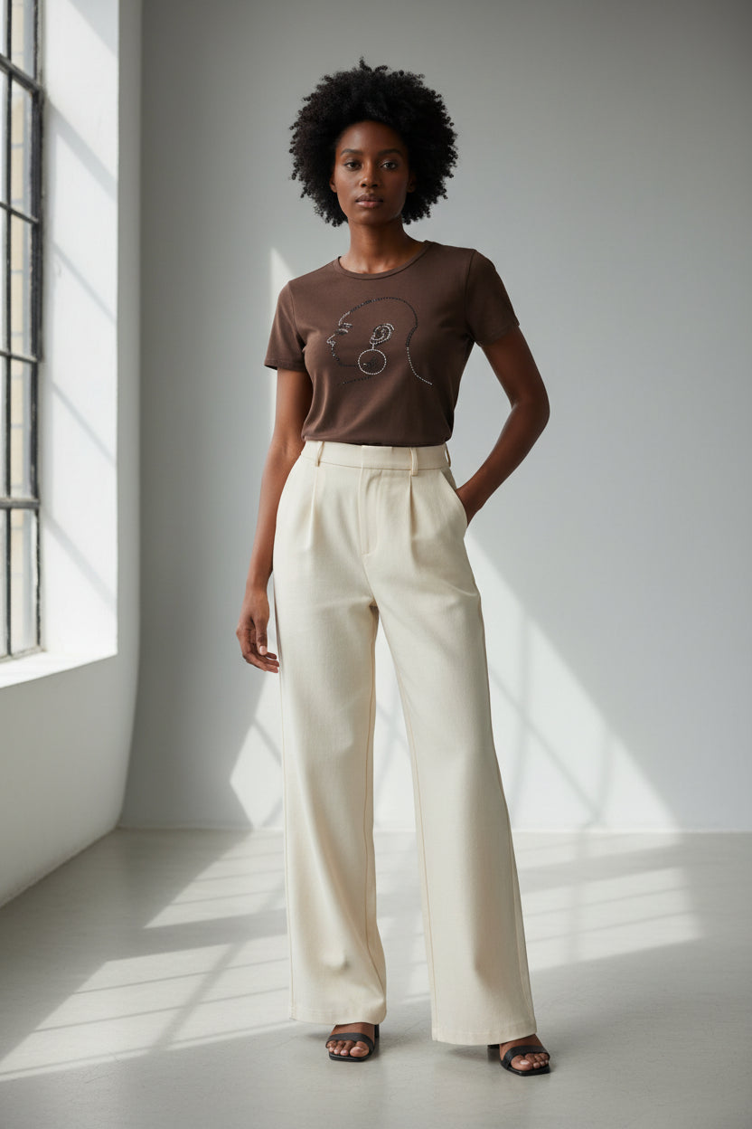 Brown Bald and Beautiful women's t-shirt with rhinestone bald head design, paired with cream pants.