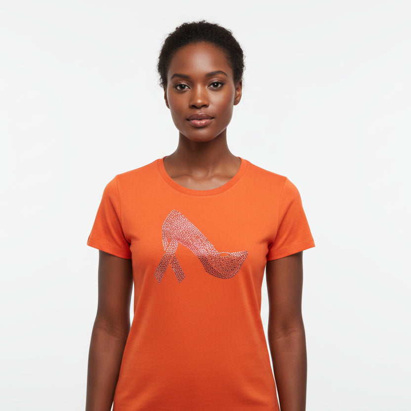 Woman in an orange t-shirt with a rhinestone stiletto shoe and pink ribbon heel design.