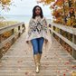 Woman walking on a wooden boardwalk with autumn foliage, wearing a silk shawl.
