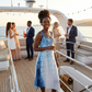 Woman in a blue dress standing on a yacht with friends in the background