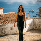  She is wearing a sleeveless black one-piece jumpsuit with green and black striped side panels 