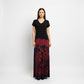 A woman modeling a long-sleeve maxi dress with a solid black v-neck top and a dark tie-dye skirt.