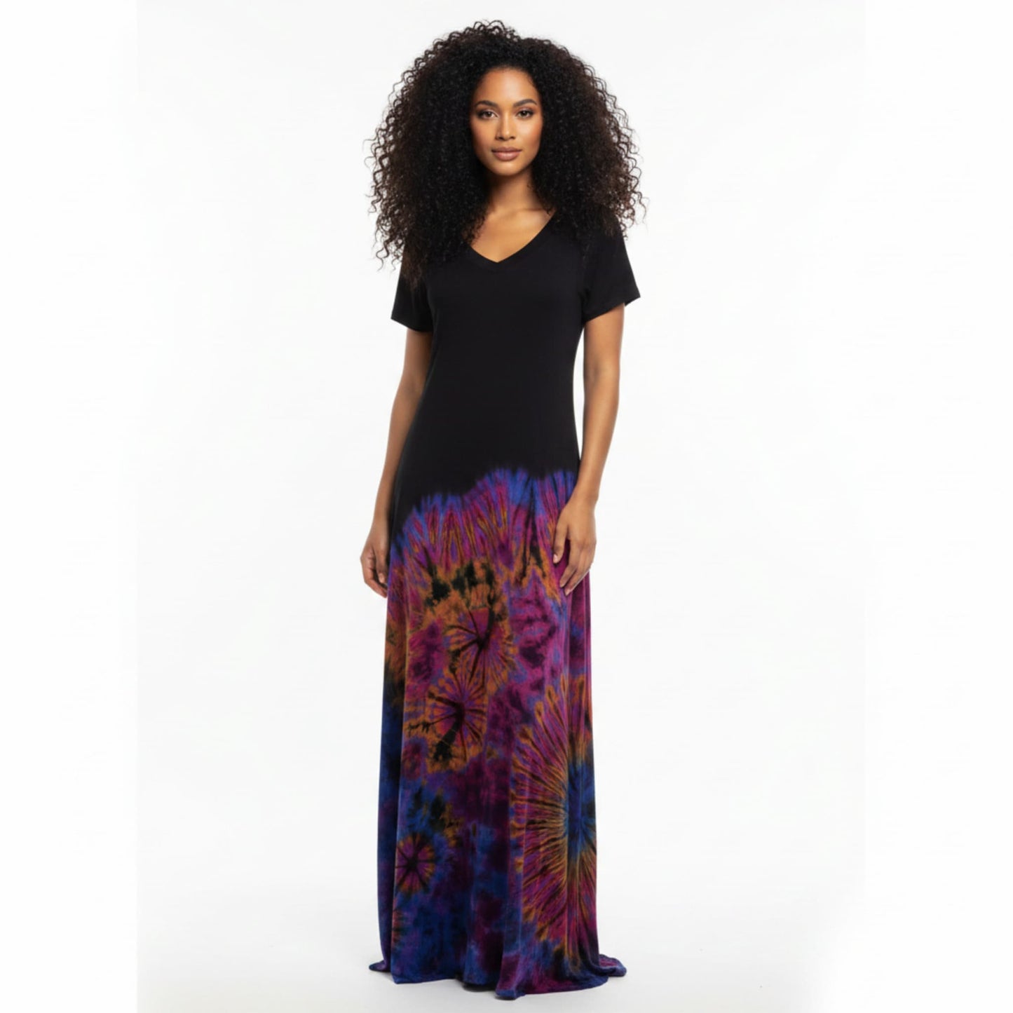 A woman modeling a long-sleeve maxi dress with a solid black bodice and a colorful tie-dye skirt.