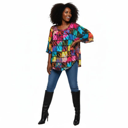 Woman wearing a colorful patterned patchwork top and blue jeans on a white background