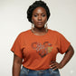 Woman in an orange "I Love Chocolate" rhinestone t-shirt with pearl oval stones and reflective film.