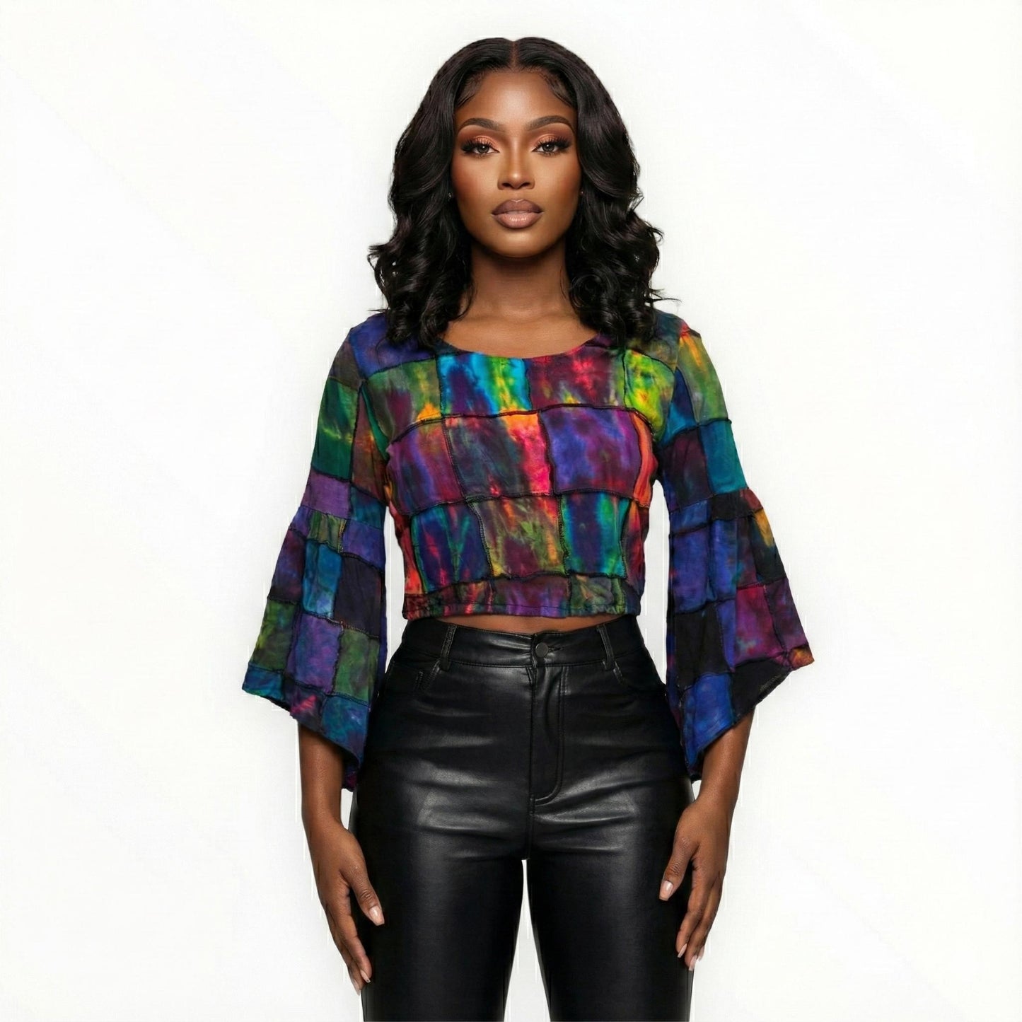 Woman wearing a tie dye top and leather pants on a white background