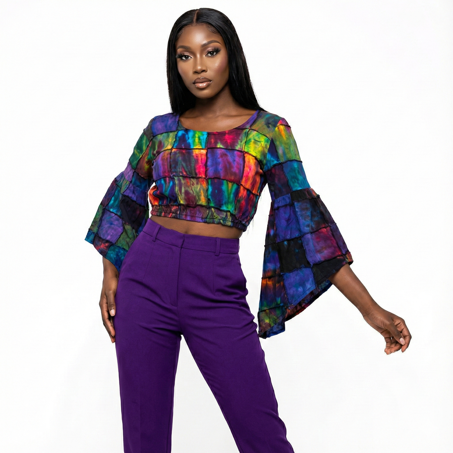 Woman wearing a tie dye  top and purple pants on a white background