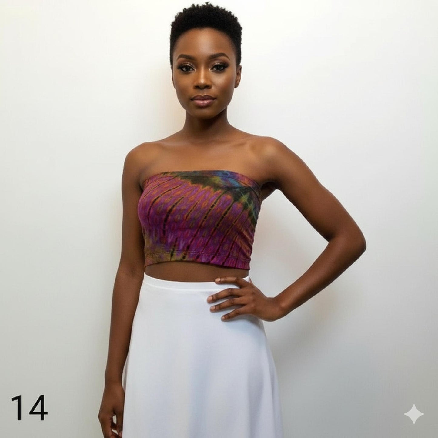 Woman wearing a colorful tube top and white skirt against a plain background