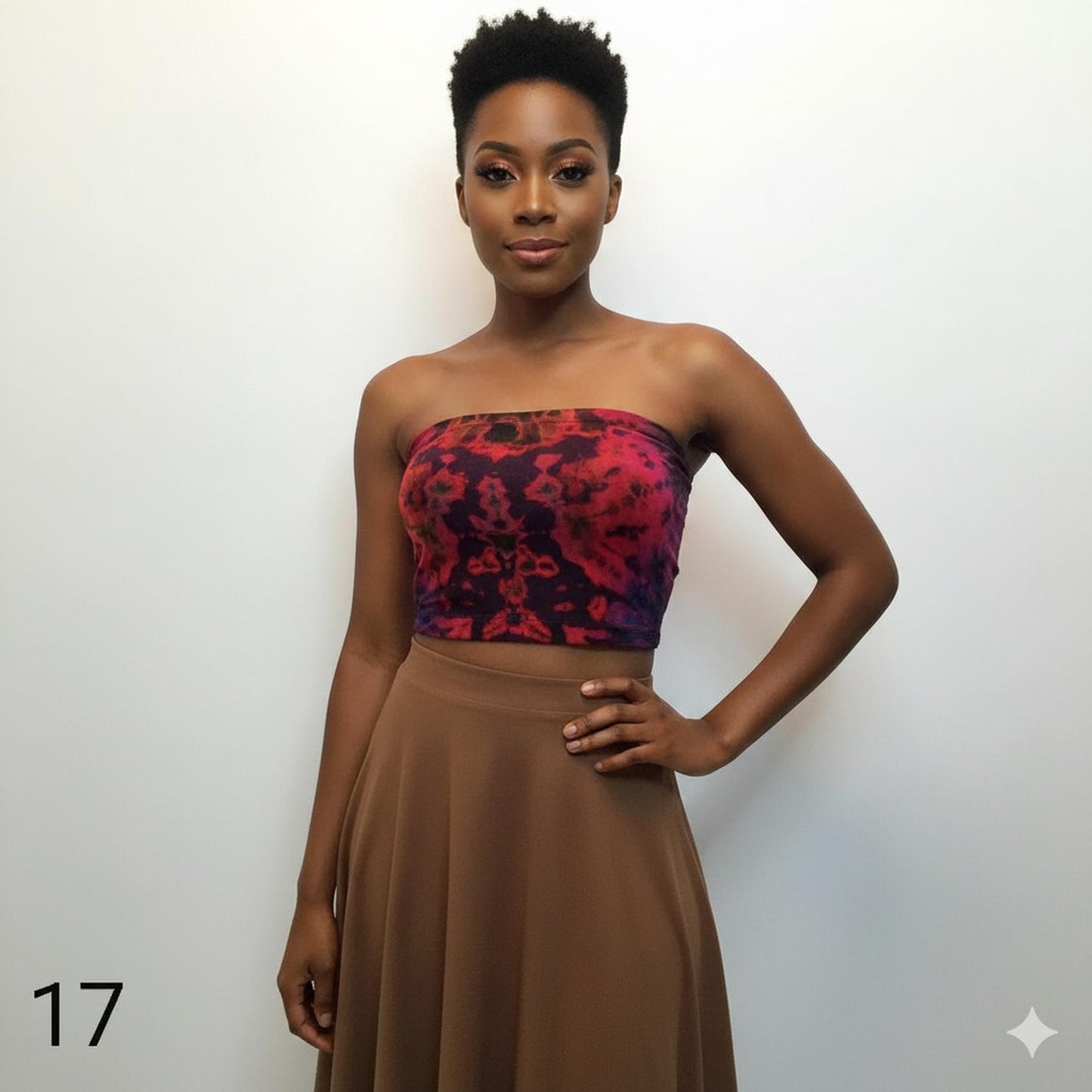 Woman wearing a tie dye tube top with a red and black pattern and a brown skirt against a white back