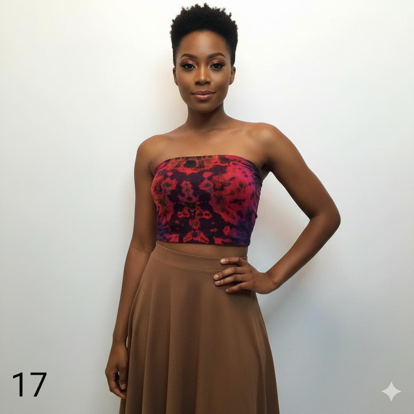 Woman wearing a tie dye tube top with a red and black pattern and a brown skirt against a white back