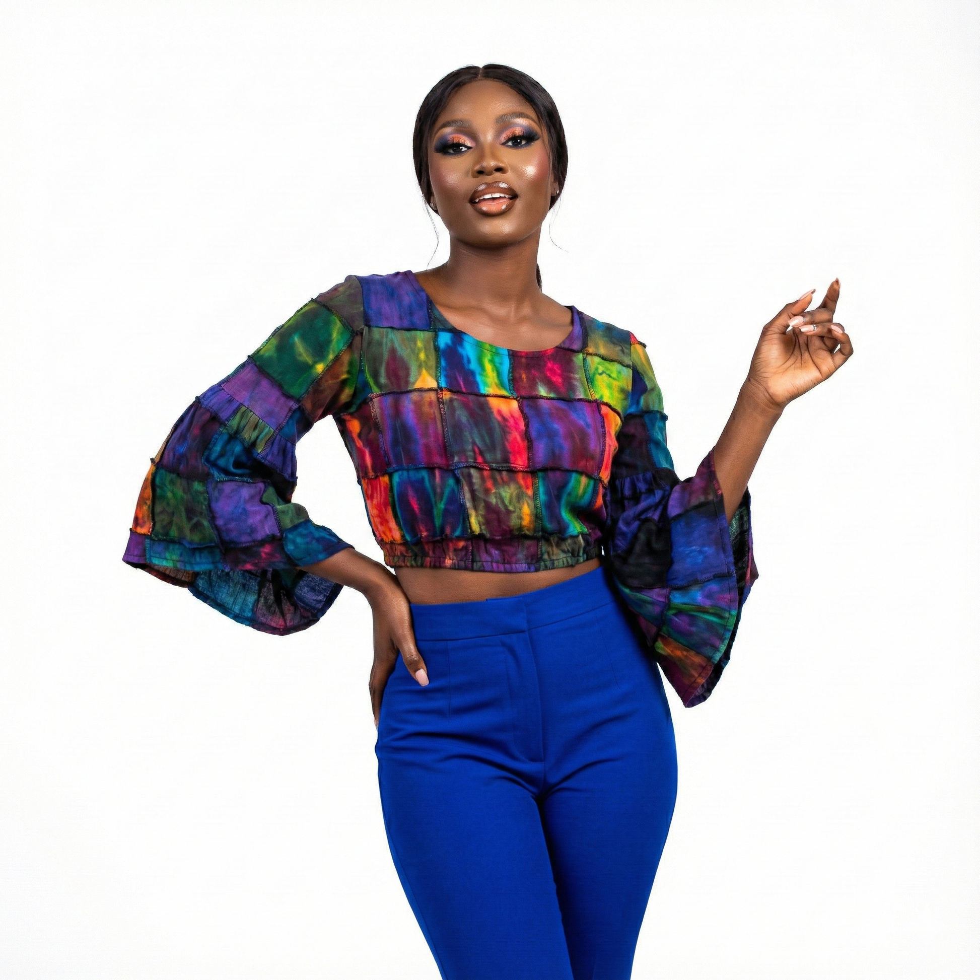 Woman wearing a tie dye top  and blue pants on a white background