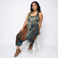 Woman wearing a tie-dye jumpsuit sitting on a white stool against a white background