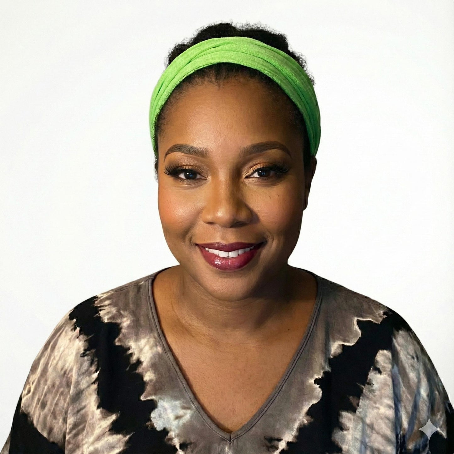 Woman wearing a green headband and tie-dye shirt on a white background