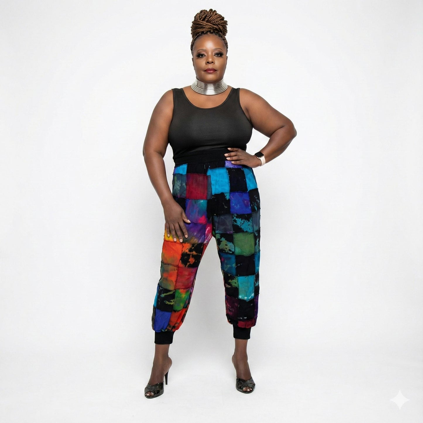 Woman wearing a black top and colorful patchwork pants on a white background