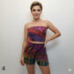 Woman wearing a colorful tie-dye tube top and shorts set on a plain background