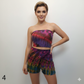 Woman wearing a colorful tie-dye tube top and shorts set on a plain background