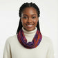 Woman wearing a colorful tie dye scarf and white turtleneck against a plain background