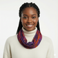 Woman wearing a colorful tie dye scarf and white turtleneck against a plain background