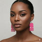 Woman wearing pink earrings against a neutral background