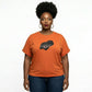Woman in an orange t-shirt with a black rhinestone and metallic film design, dark jeans, earrings.