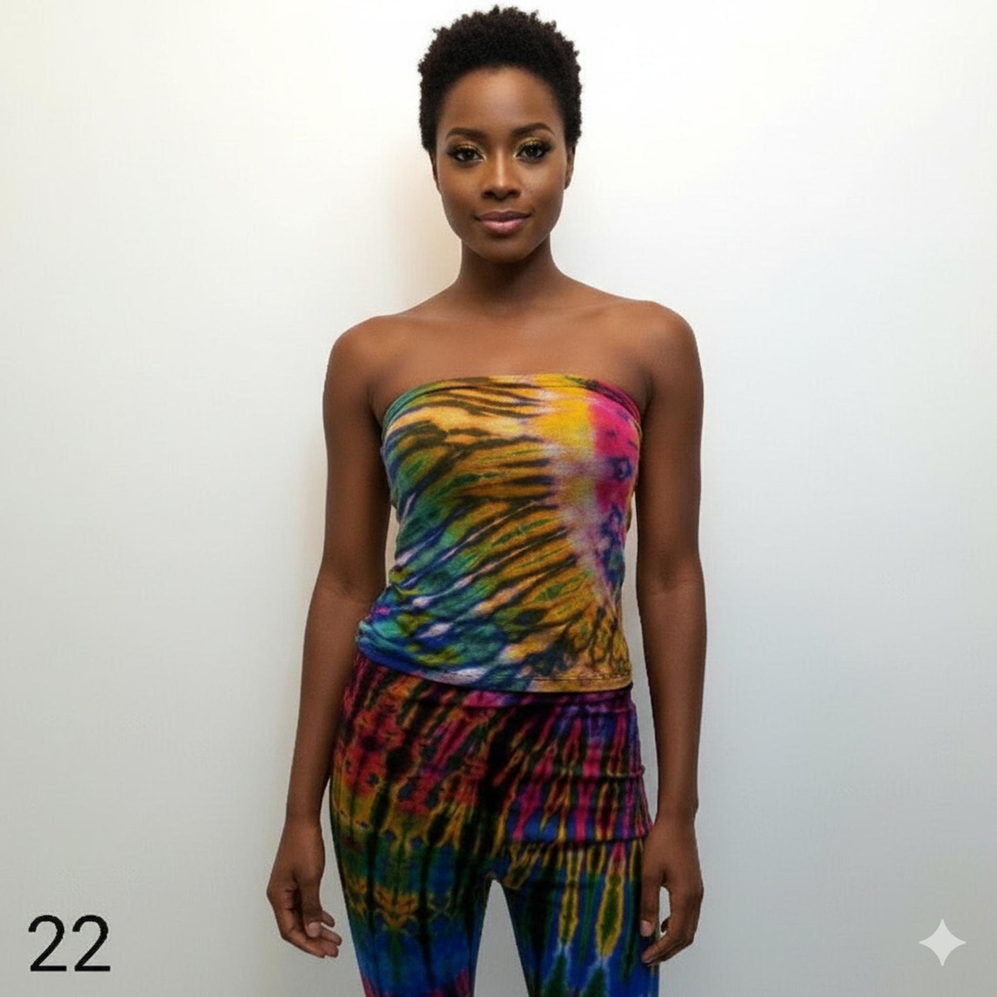 Woman wearing a colorful tie-dye tubes top and pants against a white background