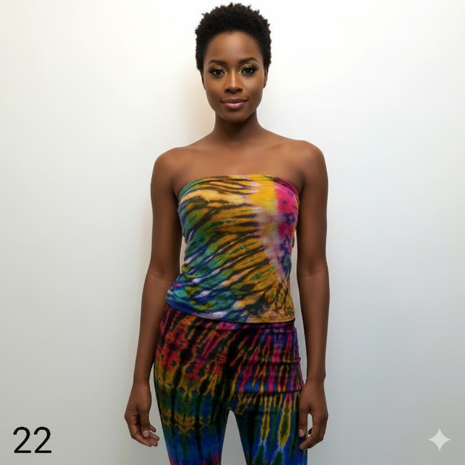 Woman wearing a colorful tie-dye tubes top and pants against a white background