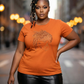 Woman in an orange t-shirt with a rhinestone loc design, black leather pants