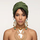 Woman wearing a green turban, gold necklace with Africa map, and earrings on a light gray background