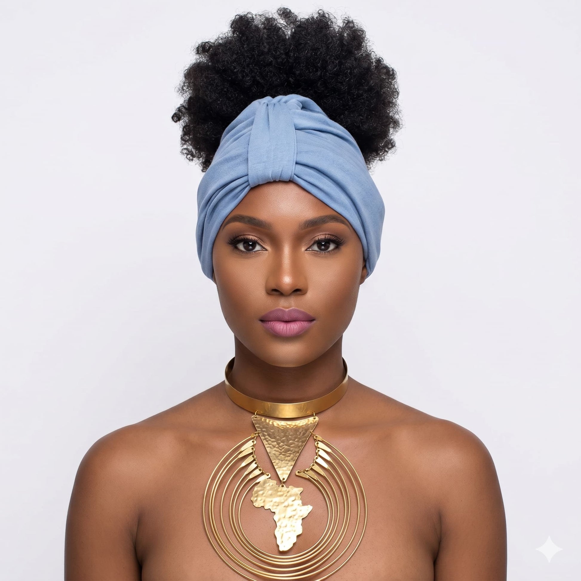 Woman wearing a blue turban and gold necklace on a white background