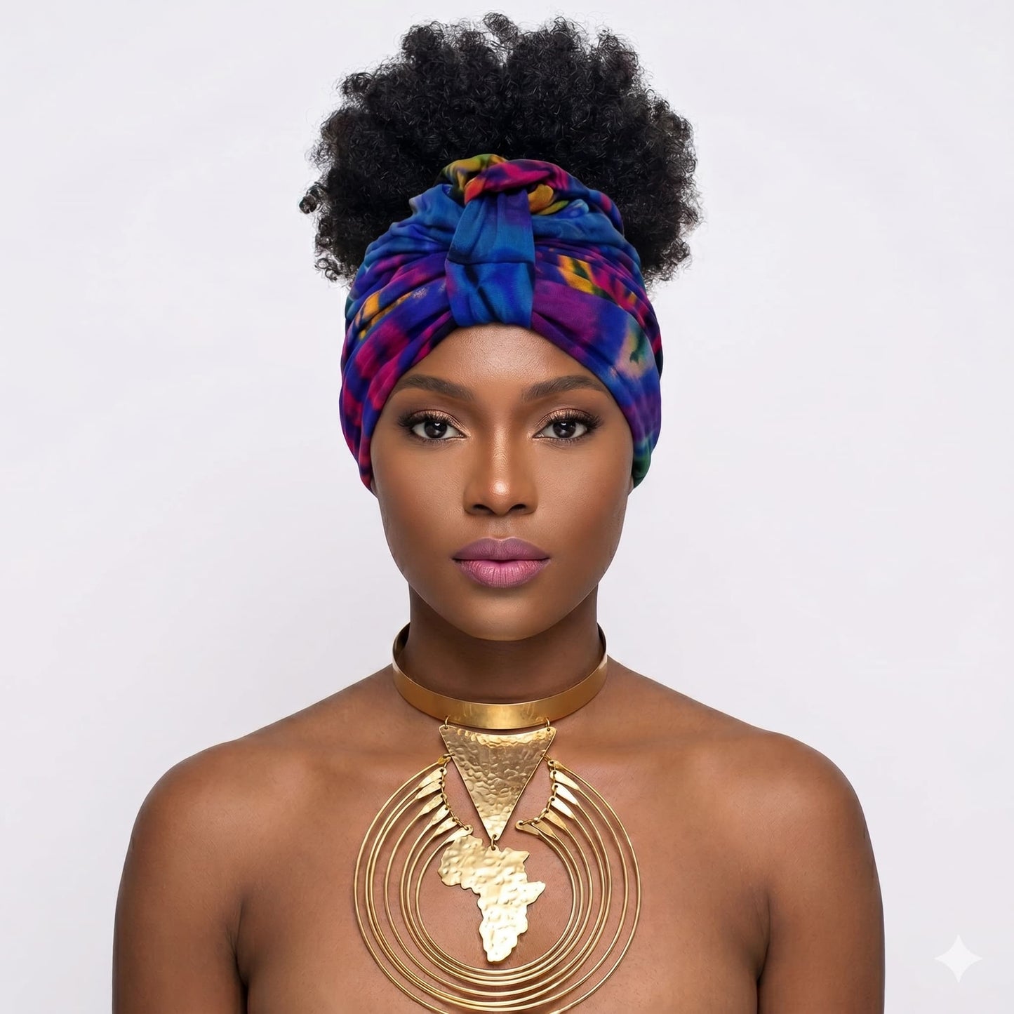 Woman wearing a tiedye turbanl  and gold necklace on a white background