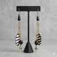 Handcrafted brass, black and white striped bone, and black bead drop earrings with yellow accents.