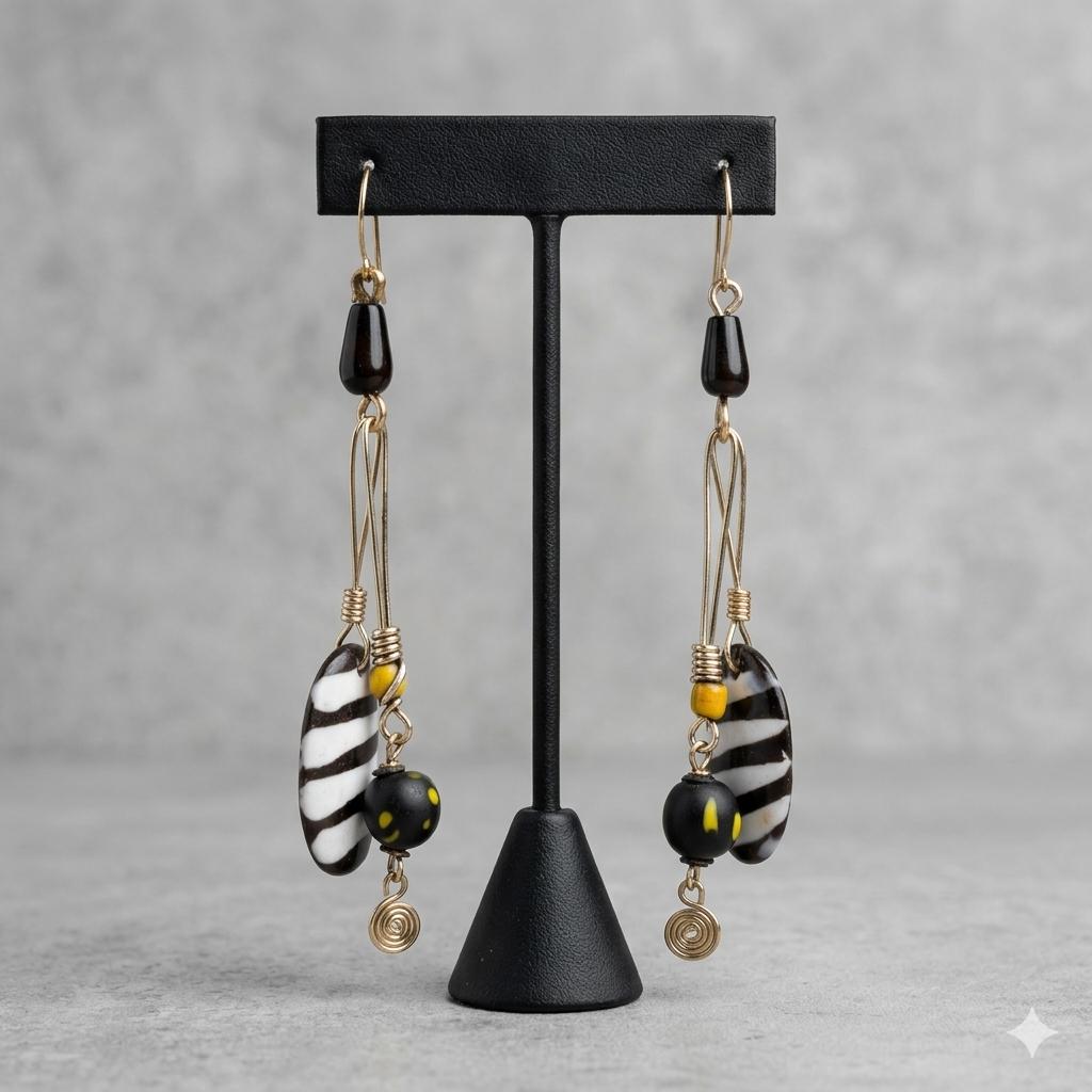 Handcrafted brass, black and white striped bone, and black bead drop earrings with yellow accents.