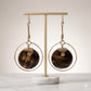 Kenyan handcrafted brass hoop earrings with dark, polished bone discs and wire-wrapped details.