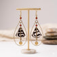 Kenyan brass, and bone drop earrings with black and white patterns on a display stand.