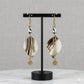 Kenyan brass, cowrie shell, and hand-carved bone drop earrings with a spiral design.