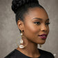 Woman wearing gold hoop earrings with shells against a neutral background