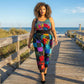 Woman in a colorful patchwork jogger  walking on a wooden boardwalk by the ocean.