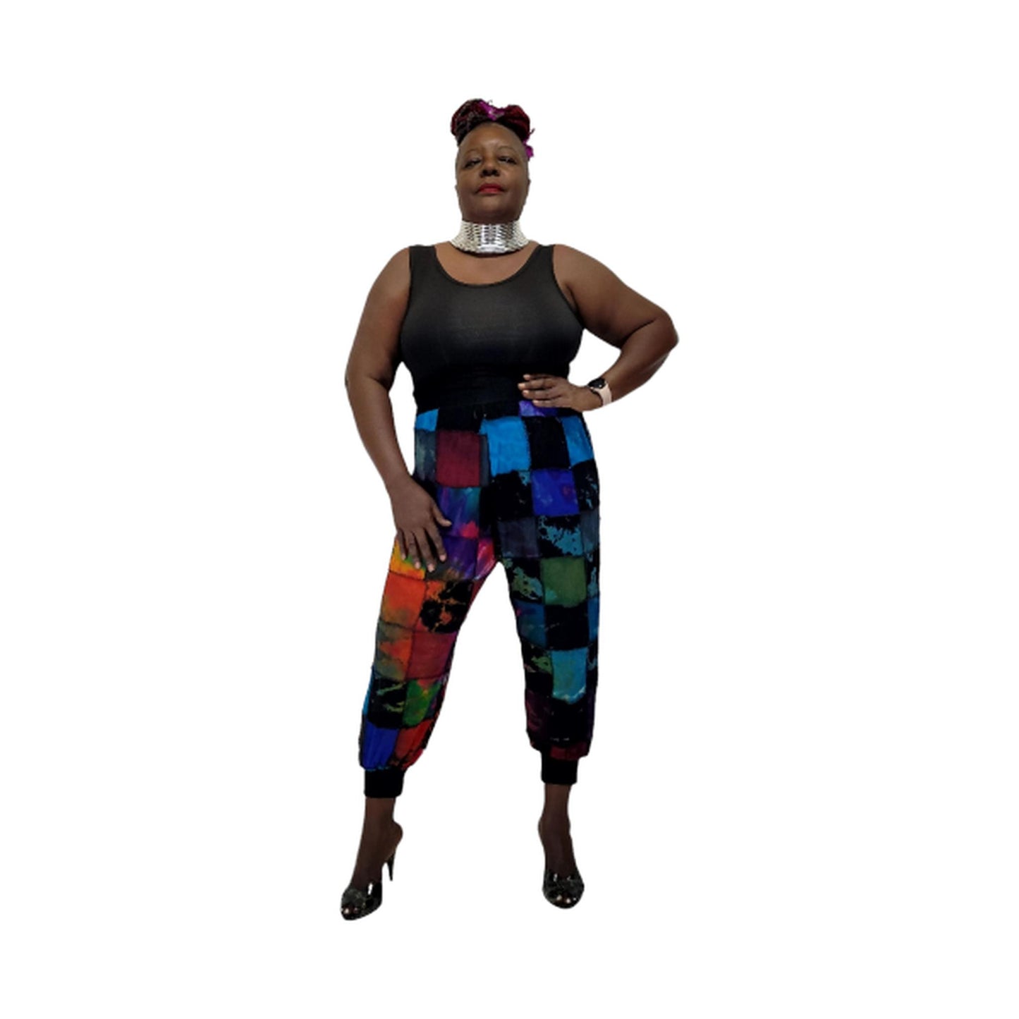 Woman wearing a black sleeveless top and colorful patchwork pants on a white background