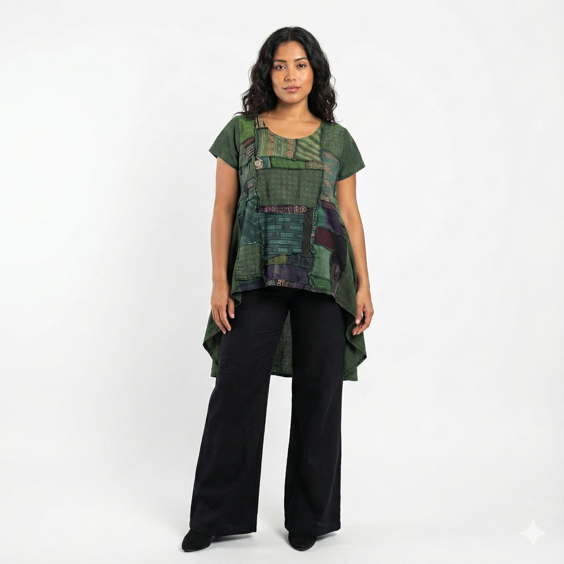 Woman wearing a green patterned top and black pants on a white background