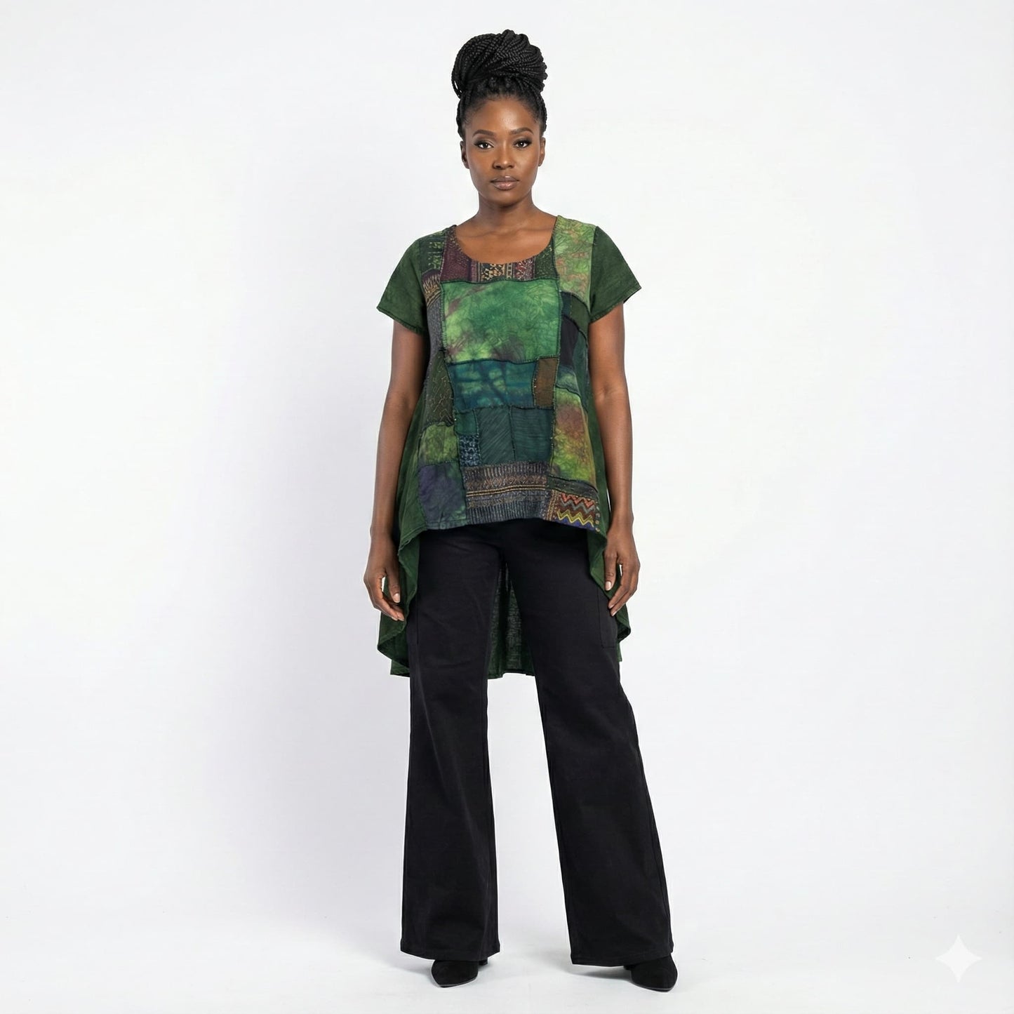 Woman wearing a green and black patterned top with black pants on a white background