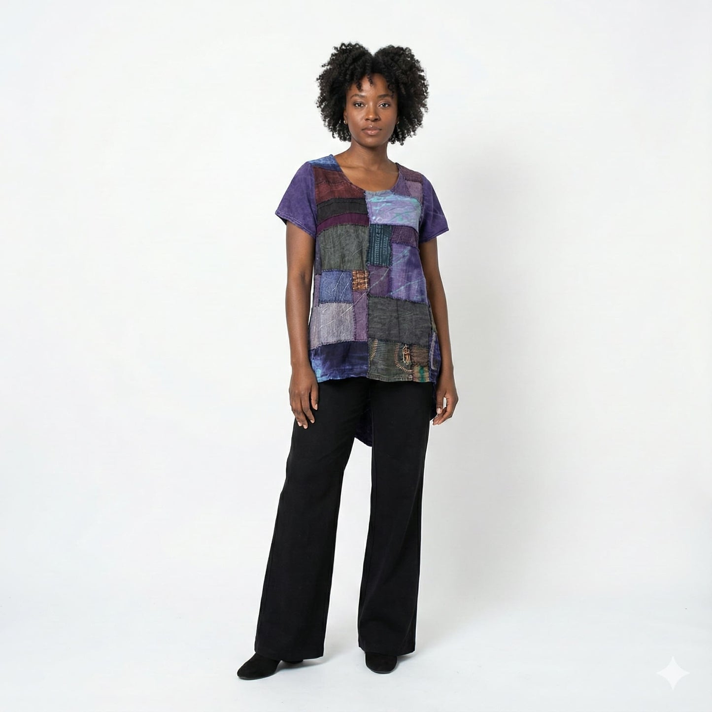 Woman wearing a colorful patchwork top and black pants on a white background