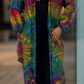 A person standing on the street wearing a multicolored tie-dye duster with long sleeves and a V-neck.