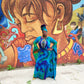 Woman in a colorful dress standing in front of a vibrant mural-Sanjules