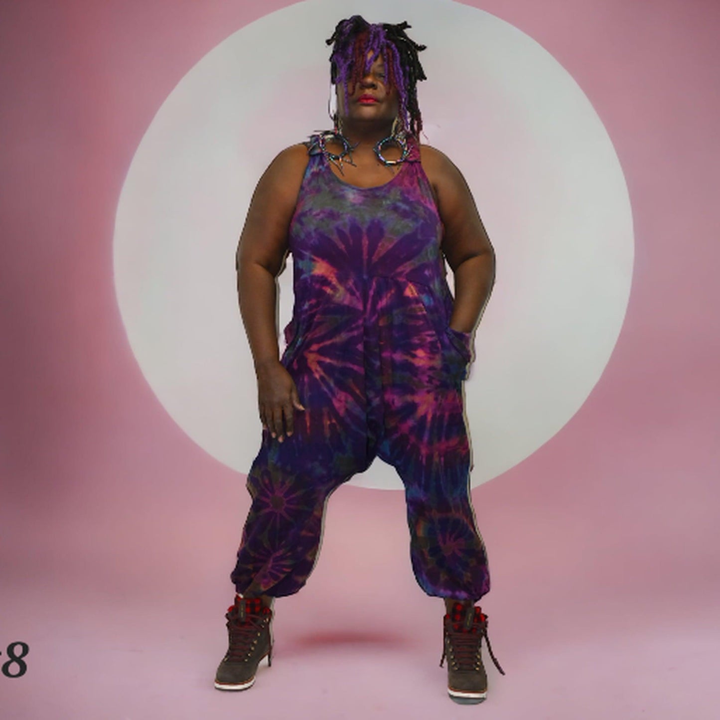 Person wearing a tie-dye jumpsuit on a pink background SanJules