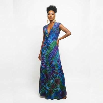 A woman modeling a sleeveless, floor-length wrap maxi dress with a vibrant tie-dye pattern