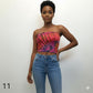Woman wearing a colorful tube top and blue jeans against a white background