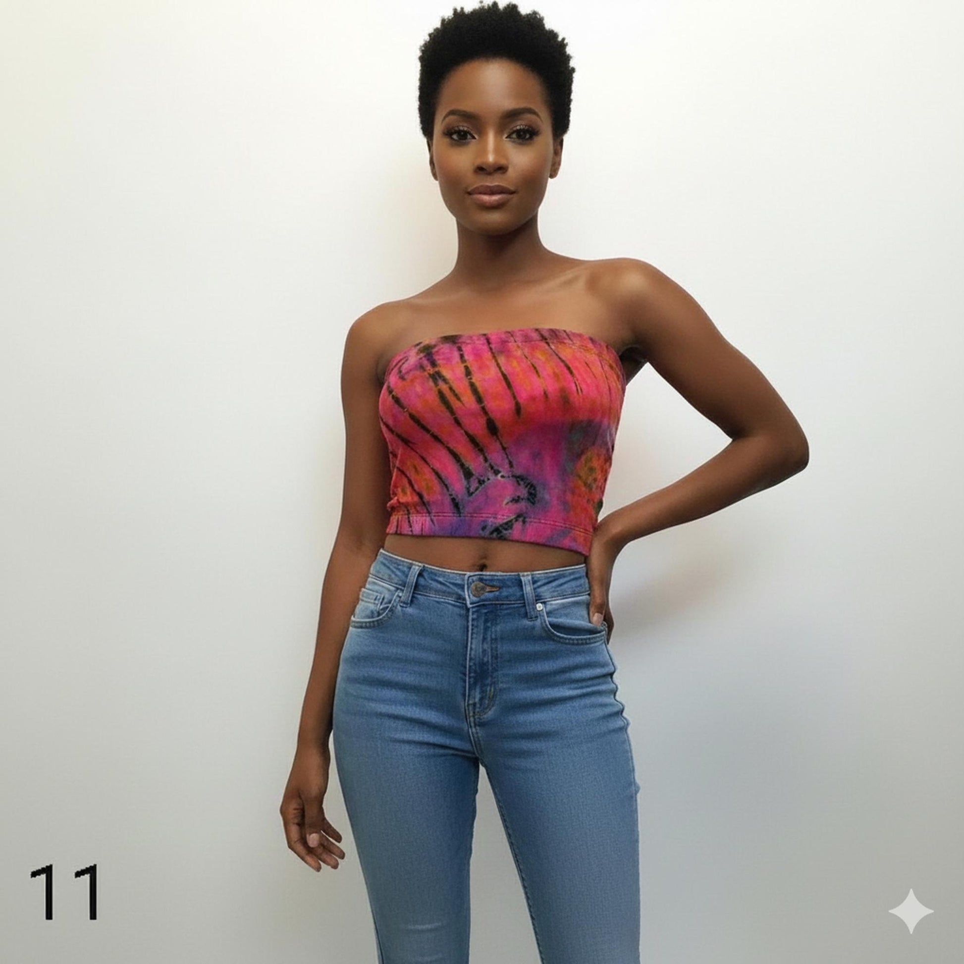 Woman wearing a colorful tube top and blue jeans against a white background