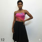 Woman wearing a pink tie-dye tube top and black skirt on a white background